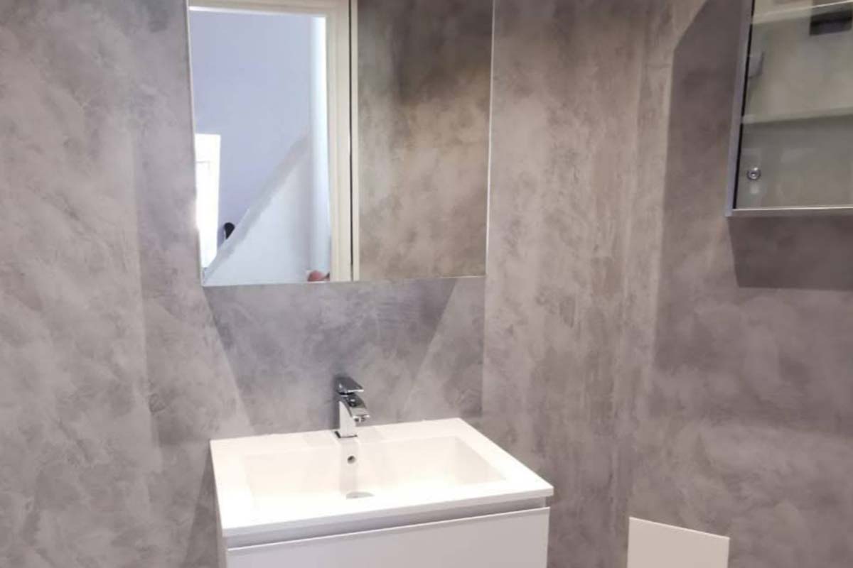 Ett badrum med väggar i grå microcement