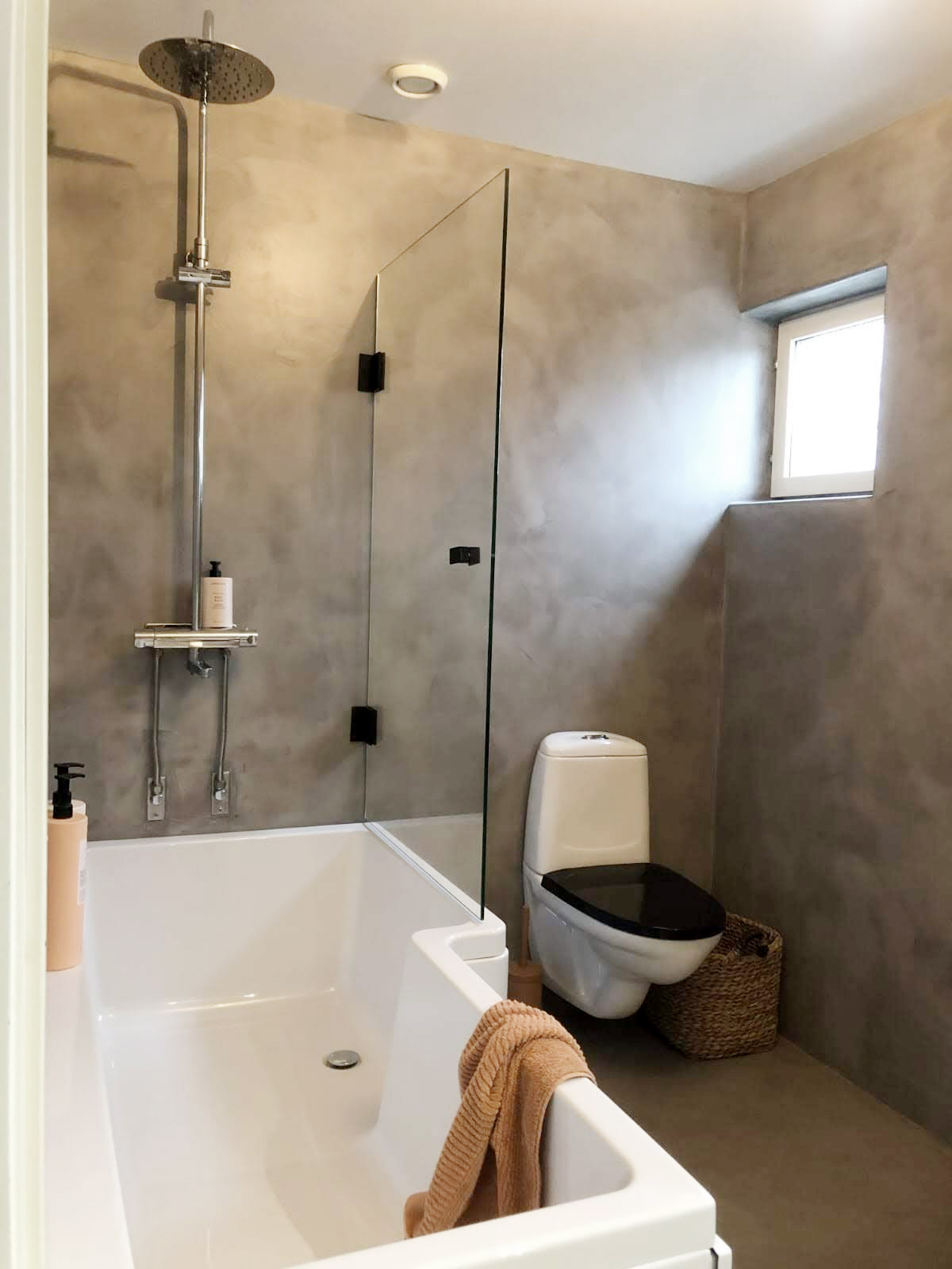 Ett badrum med gråbruna väggar i microcement